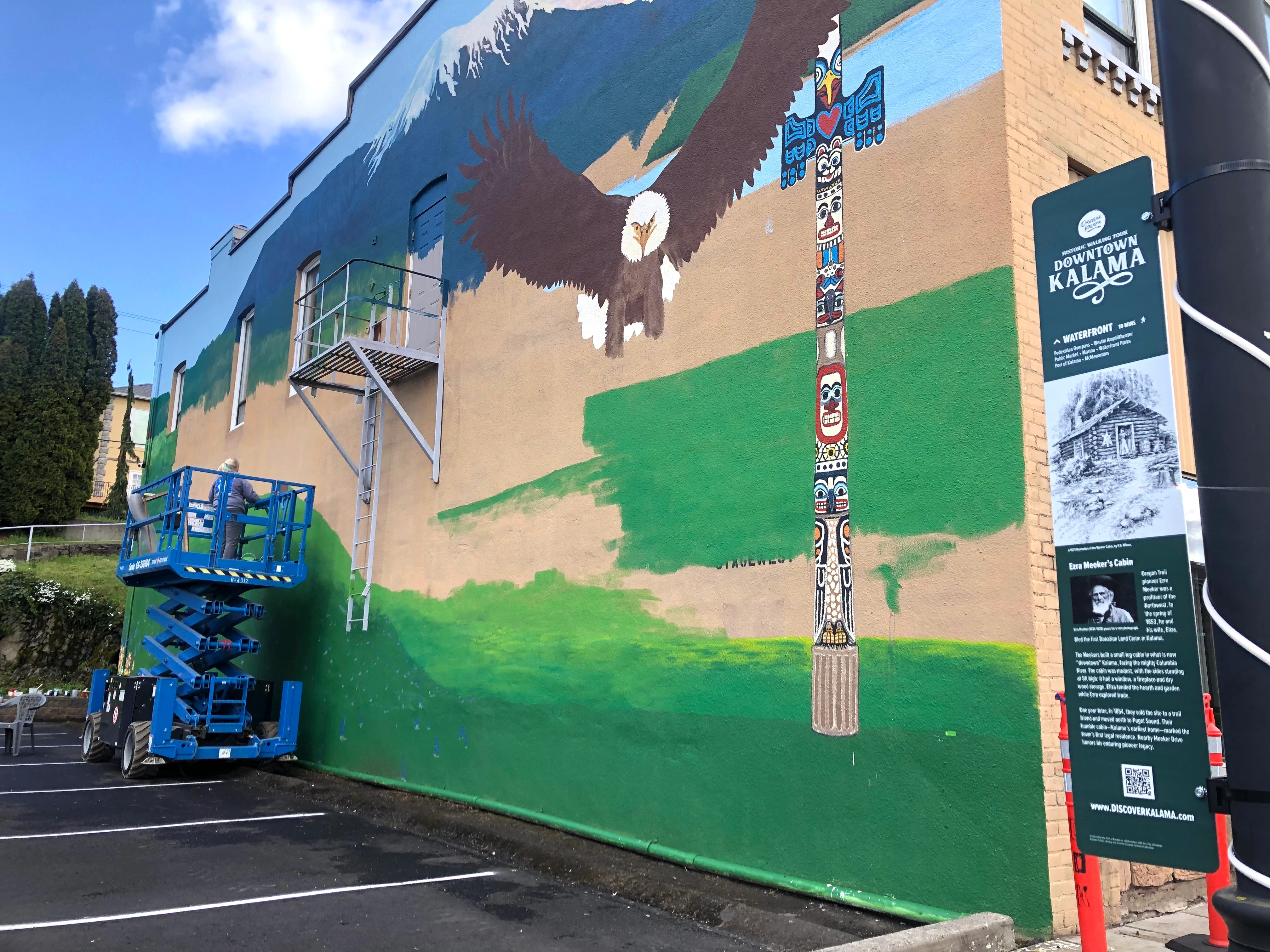Terri Van Matre paints the downtown Kalama mural as a newly installed History Blade stands in the foreground, First Street, Kalama, April 2026