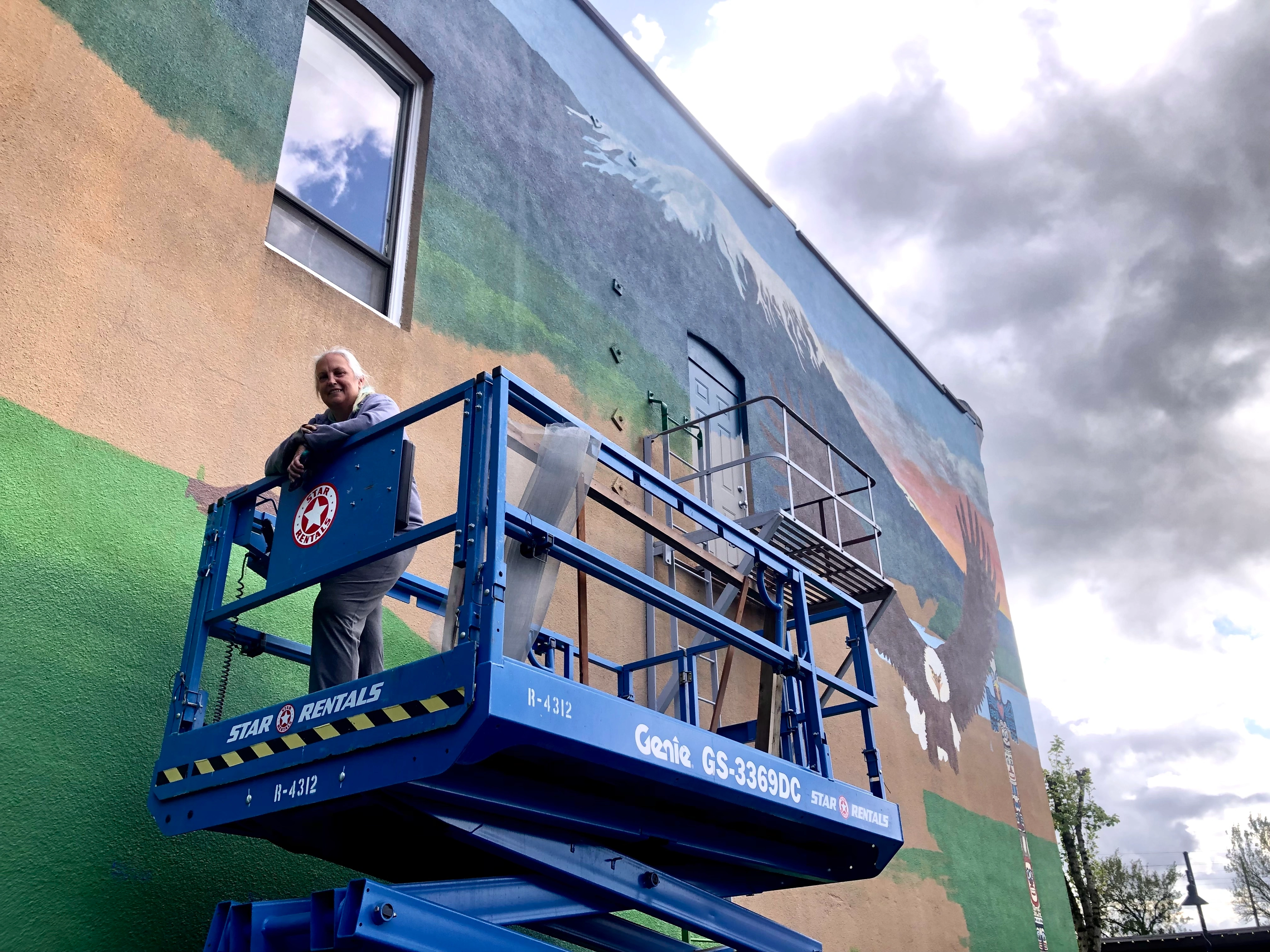 Terri Van Matre paints the downtown Kalama mural as a newly installed History Blade stands in the foreground, April 2026